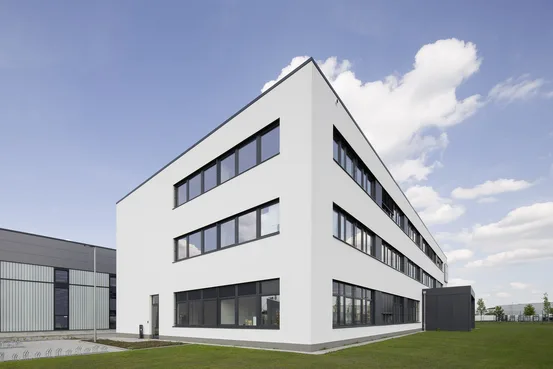 Weißes, modernes Bürogebäude mit Fensterbändern unter blauem Himmel